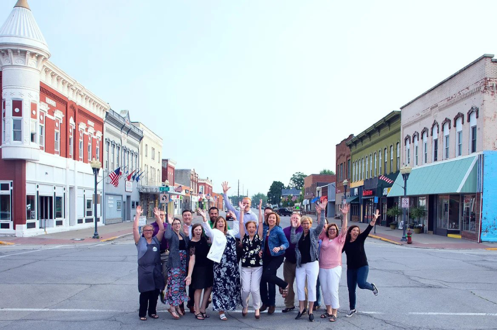 Group of community members happily cheering in the middle of main street with a view of the historic main street building in the back